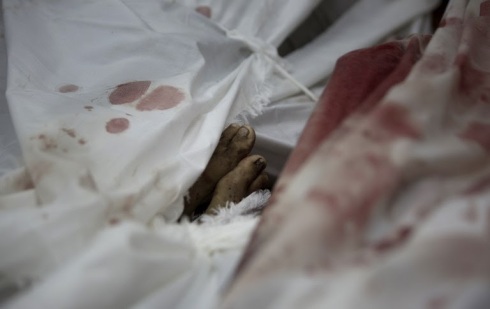 The body of Ali al-Shibari, a 10-year-old Palestinian child who was killed after a UN school in the northern Beit Hanun district of the Gaza Strip was hit by an Israeli shell, lies wrapped in shrouds at the morgue of the Kamal Adwan hospital in Beit Lahiya on July 24, 2014: photo by Mahmud Hams / AFP, 24 July 201